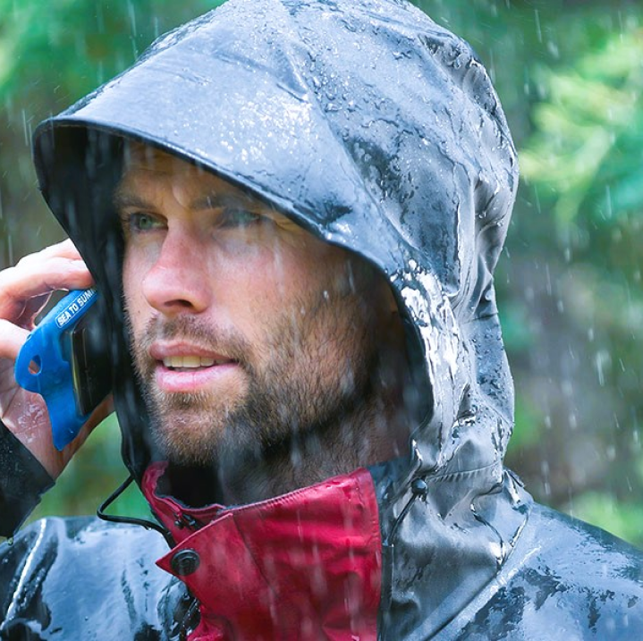 aman wearing a rain jacket during rain and making a phone call